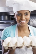 Mixed Race female chef holding eggs