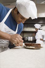 Hispanic male pastry chef decorating cake