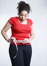 Mixed race woman measuring her waistline