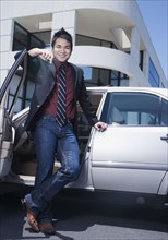 Asian businessman leaning on car
