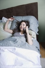 Woman talking on phone in bed