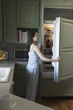 Woman opening refrigerator door