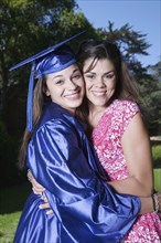 Mother hugging graduate daughter