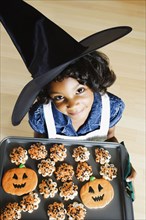 African girl holding Halloween cookies