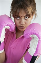 Hispanic woman wearing pink boxing gloves