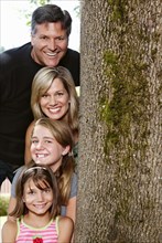 Smiling Caucasian family near tree trunk