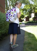 Caucasian school girl walking with backpack