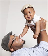 African American man lifting baby son into the air