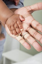 Close up of African American father and baby son's hands