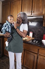 Black grandmother feeding grandson in kitchen