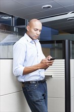 Mixed race businessman text messaging on cell phone in office