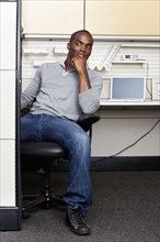 Mixed race man sitting in office cubicle