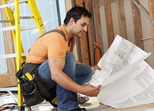 Hispanic construction worker looking at blueprints