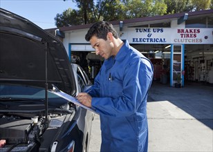 Middle Eastern mechanic writing on clipboard