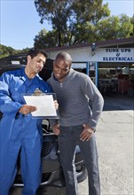 Mechanic explaining paperwork to customer