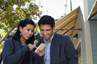 Mixed race couple using cell phone outdoors
