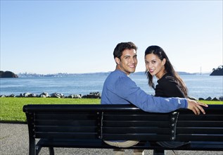 Mixed race couple sitting on park bench