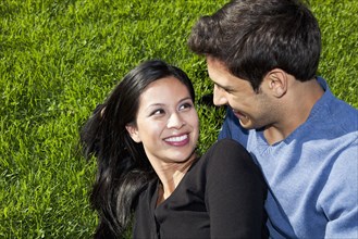 Mixed race couple relaxing together in grass