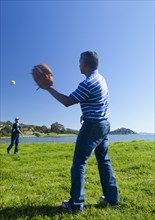 Hispanic father and son playing catch in park