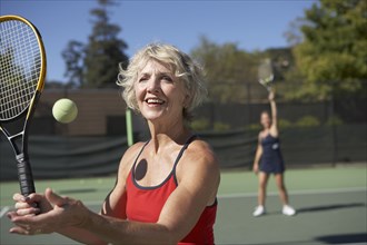 Caucasian women playing tennis on court