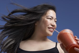 Chinese woman drinking smoothie outdoors