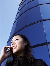 Chinese woman talking on cell phone by highrise