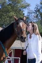 Mixed race girl kissing horse on ranch