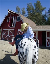 Mixed race girl riding horse on ranch