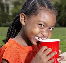 Black girl having drink outdoors