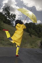 Indian woman wearing raincoat and rainboots with umbrella