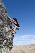 Hispanic climber scaling steep rock face