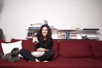 Middle Eastern woman watching television on sofa
