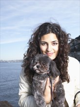 Middle Eastern woman holding dog outdoors