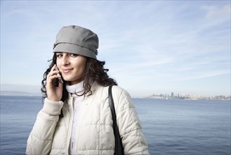 Middle Eastern woman talking on cell phone by waterfront