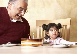 Senior Hispanic man and granddaughter celebrating birthday