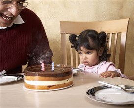 Senior Hispanic man and granddaughter celebrating birthday