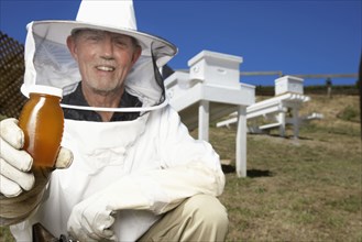 Caucasian beekeeper holding jar of honey