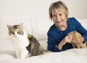 Senior Caucasian woman petting cats on bed