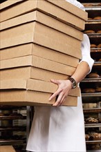Hispanic baker carrying stack of boxes in bakery