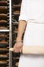 Hispanic baker holding rolling pin in bakery
