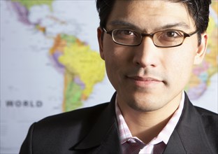 Mixed race businessman standing by world map