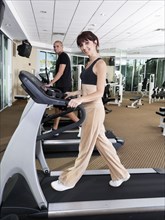 Couple using exercise machines at gym