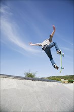 Caucasian teenage boy doing tricks in skate park