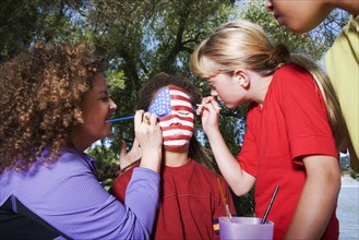Children painting American flag on friend's face