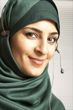 Middle Eastern woman wearing headset over scarf