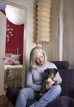 Senior Caucasian woman petting dog in armchair