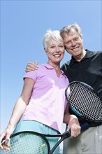 Senior Caucasian couple holding tennis rackets