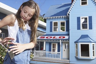 Mixed race girl playing with doll house