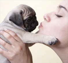 Mixed race woman kissing pug's nose