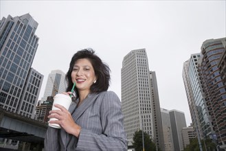 Chinese businesswoman drinking coffee on city street